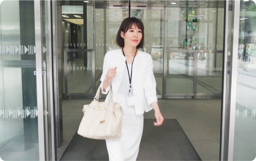 オフィスビルの入り口を出る女性社員の様子
